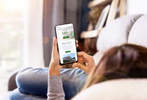 A woman uses the Ivy Bank app while sitting on the couch.