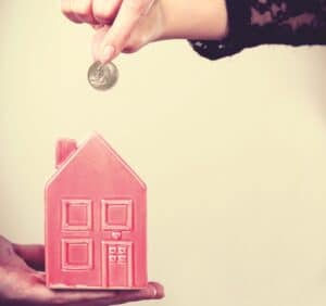 People hands with little house and silver coin.