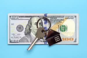 house or apartment key, dollars banknote isolated on blue background