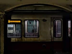 An MBTA Red Line train sits stopped in a darkened Kendall Square subway station.