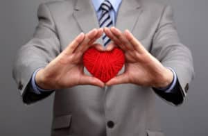 Man holding a red woolen heart concept for valentine's day, business customer care, charity, social and corporate responsibility