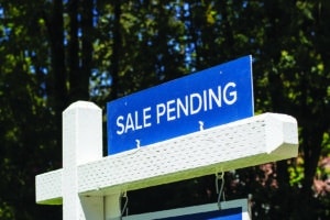 Closeup of a "Sale Pending" real estate sign outside a residential single-family house on the market. Pandemic housing market frenzy concept.