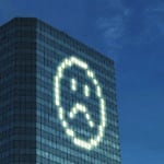 office tower with lights on different floors and rooms turned on to illuminate a frowning-face emoji