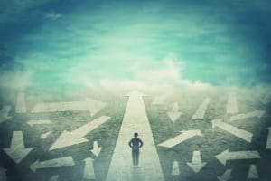 Doubtful person, hands on hips, choosing the way as multiple arrows on the road showing a mess of different directions. Choosing the correct pathway, difficult decision concept, confusion symbol.