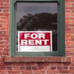 FOR RENT sign in the window of an old brick building