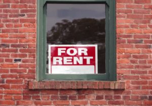 FOR RENT sign in the window of an old brick building