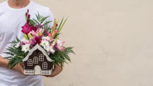Man holds beautiful floral arrangement in a house-shaped box. Gardening concept