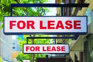 Two For Lease signs on display outside buildings during daytime concept