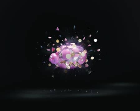 Piggy bank suspended in mid-air against a black background explodes, sending coins flying