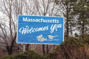 A sign reading "massachusetts welcomes you" greets highway drivers entering the state.