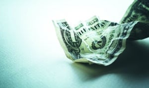 Close-up photo of a dollar bill lying crumpled on a white tablecloth.