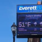 A close-up shot of Everett Bank's sign at its main branch in Everett Square, Massachusetts. Digital display on the sign shows the weather.