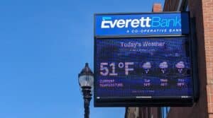 A close-up shot of Everett Bank's sign at its main branch in Everett Square, Massachusetts. Digital display on the sign shows the weather.
