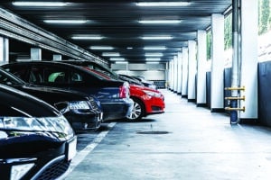 Red car paked in underground garage with lots of vehicles parking