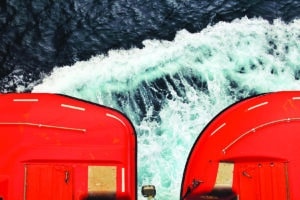 image of lifeboats on cruise ferry, seen from above with ship's wake below them