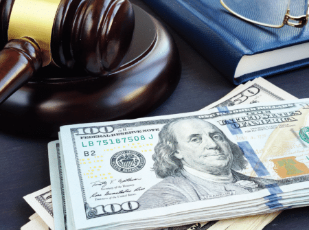 a stock photo of a gavel sitting next to a pile of $100 bills