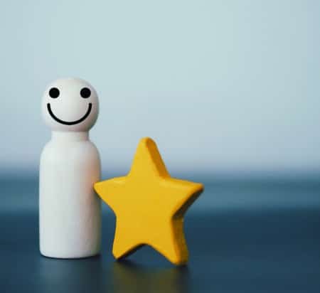 Wooden smile peg doll and yellow star. Concept of the best satisfaction. Vertical image