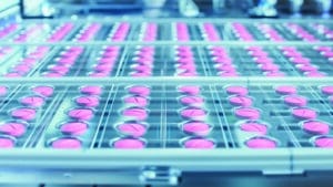 Macro Shot of Pink Pills During Production and Packing Process in a Modern Pharmaceutical Factory.