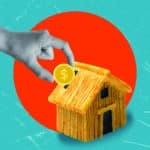 A hand is shown putting a gold coin into a miniature house-shaped piggy bank. The house is made of wood and has a roof made of straw. The background is a bright orange circle against a teal blue background.