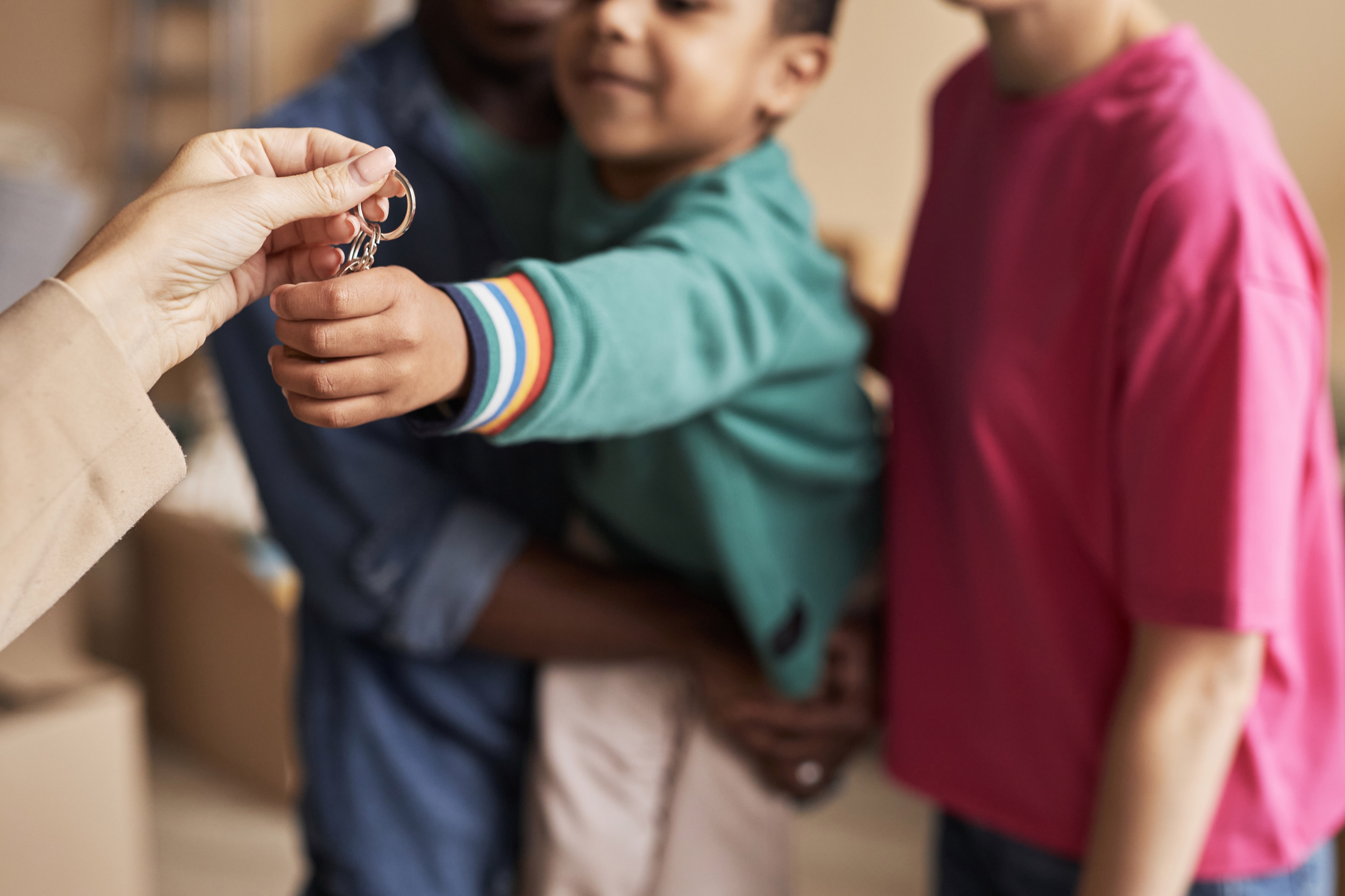 Focus on hands of young real estate agent passing key from new apartment to child held by his father after making deal and relocation