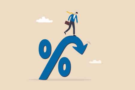 businessman standing on percentage sign looking at an arrow falling down.