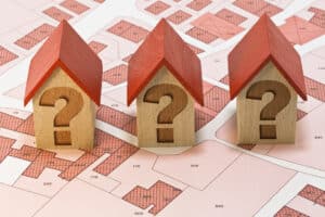 Imaginary cadastral map of a town with three wooden toy houses with question marks instead of windows