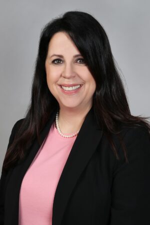 A headshot of Jennifer St. Pierre wearing a suit jacket and a pink blouse.