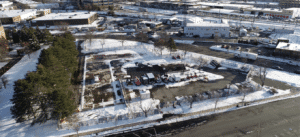 An aerial photo of 90 Washington St. in Somerville in the snow. The former strip mall's buildings have been demolished leaving a large triangle of concrete.