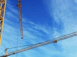 Two construction cranes against a blue sky