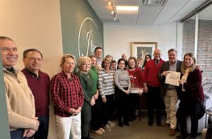 Agents, staff and executives of J Barret & Company pose for a photo with Grateful Friends President Becky Beckman, right, at the brokerage's Beverly office.