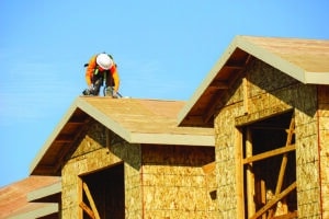 Richland, WA - July 28, 2023: Roofer wearing safety equipment working on building roof