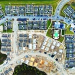 Aerial view of unfinished wooden frames of affordable houses under construction. Development of residential housing in American suburbs. Real estate market in the USA.