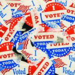 Large number of I Voted stickers and buttons stuck to window with some being removed. Illustrate destroyed ballots or missing votes due to voter fraud