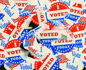 Large number of I Voted stickers and buttons stuck to window with some being removed. Illustrate destroyed ballots or missing votes due to voter fraud