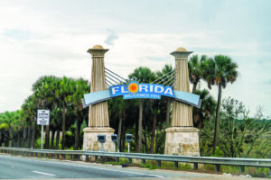 Yulee, USA - July 6, 2021: Interstate highway i95 driving car pov from Georgia state line and colorful sign on roadside for Florida welcomes you with sunny sun symbol and no stopping sign
